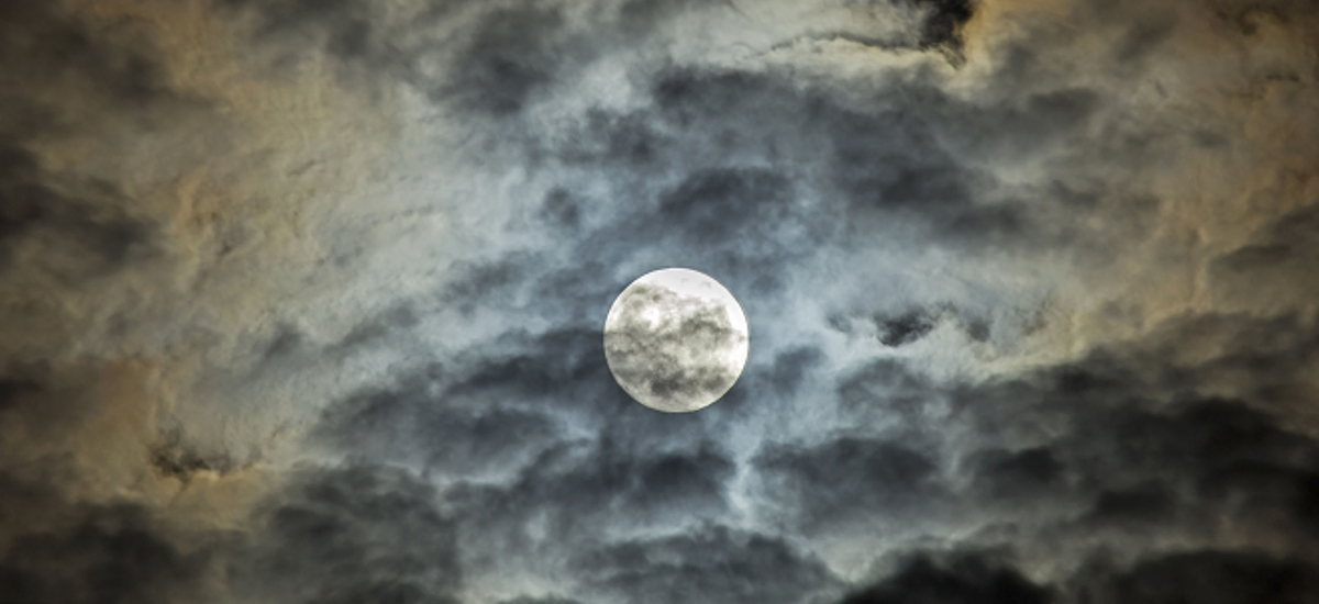 Slide Image of a bright moon faded behind thin cloud